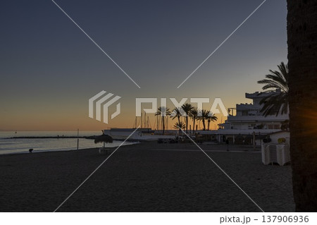Sunset over the beach in Marbella, Spain with palm trees and boats in the background Sunset over the beach in Marbella, Spain with palm trees and boats in the background 137906936