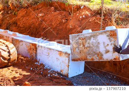 Construction workers place concrete blocks in trench at job site Construction workers place concrete blocks in trench at job site 137907210