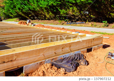 Construction of wooden deck frame takes place in residential area 137907212