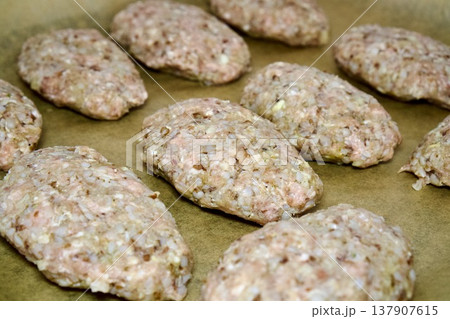Raw meat patties on baking parchment paper before cooking Raw meat patties on baking parchment paper before cooking 137907615