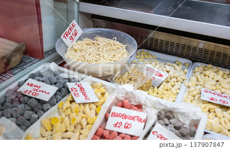 Genoa, liguria, italy. May 18, 2024. Variety of fresh homemade pasta: trofie, colorful gnocchi (squid ink, beetroot, saffron) displayed in italian market stall Genoa, liguria, italy. May 18, 2024. Variety of fresh homemade pasta: trofie, colorful gnocchi (squid ink, beetroot, saffron) displayed in italian market stall 137907847