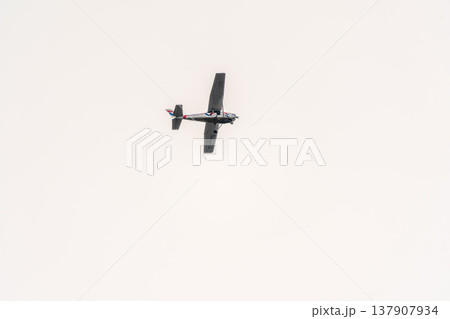 Small ultralight airplane with overhead wing and single propeller flying in sunset sky. 137907934