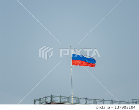 Russian tricolor flag waving in the wind against a blue sky. Russian tricolor flag waving in the wind against a blue sky. 137908104