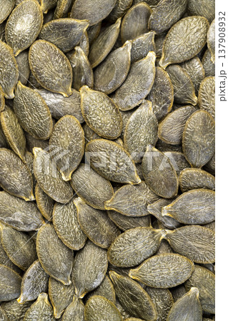 peeled large green pumpkin seeds scattered on the table, a large number of pumpkin seeds dried and ready for subsequent cooking 137908932