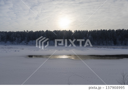 a partially frozen river in winter after frosts, a small part of the river that is not frozen after severe frosts, the rest of the river is covered with ice 137908995