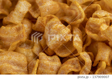 mashed potato chips fried in a large amount of sunflower oil, sprinkled with red hot pepper spices, crispy delicious high-calorie chips with spices are scattered on the table mashed potato chips fried in a large amount of sunflower oil, sprinkled with red hot pepper spices, crispy delicious high-calorie chips with spices are scattered on the table 137909007