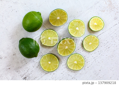 Whole lime and sliced citrus fruits on white stone like desk, view from above Whole lime and sliced citrus fruits on white stone like desk, view from above 137909218