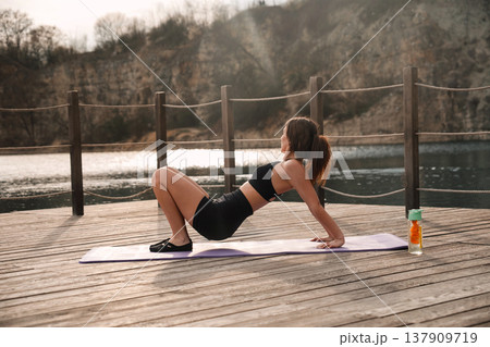 Pretty Woman Holding Bridge Yoga Pose On Mat At Lake. Outdoor Fitness And Core Stability Concept 137909719