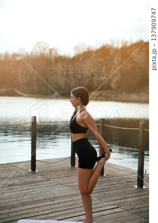 Young Woman Standing Calm After Workout Near Lake. Outdoor Fitness Lifestyle And Recovery Concept Young Woman Standing Calm After Workout Near Lake. Outdoor Fitness Lifestyle And Recovery Concept 137909747