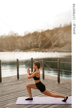 Attractive Woman Performing Deep Lunge Outdoors At Lake. Strength And Flexibility Training Concept 137909749