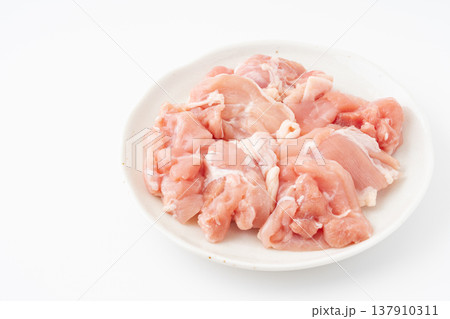 白背景にお皿に載せた生の鶏もも肉のぶつ切り 137910311