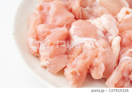 お皿に載せたぶつ切りにした生の鶏もも肉のクローズアップ お皿に載せたぶつ切りにした生の鶏もも肉のクローズアップ 137910326