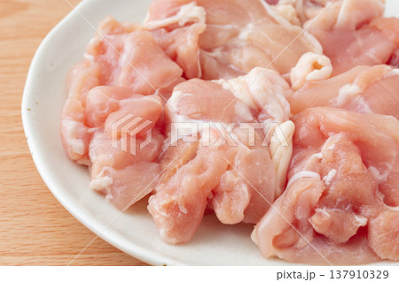 お皿に載せたぶつ切りにした生の鶏もも肉のクローズアップ お皿に載せたぶつ切りにした生の鶏もも肉のクローズアップ 137910329