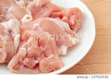 お皿に載せたぶつ切りにした生の鶏もも肉のクローズアップ お皿に載せたぶつ切りにした生の鶏もも肉のクローズアップ 137910330