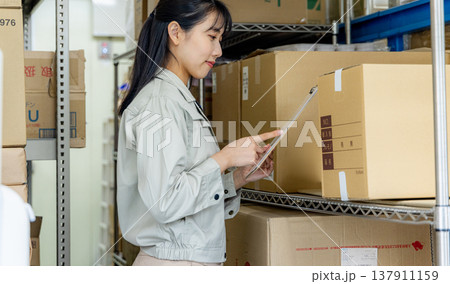 倉庫で商品チェックをする女性 倉庫で商品チェックをする女性 137911159