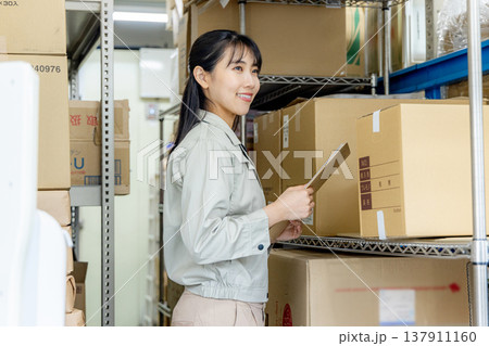 倉庫で商品チェックをする女性 倉庫で商品チェックをする女性 137911160