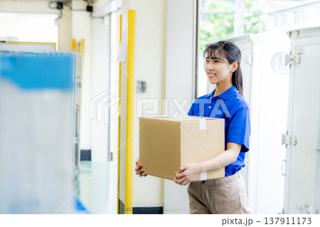 荷物を届ける宅配便の女性ドライバー 137911173