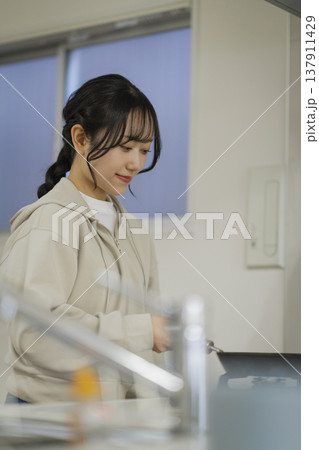 キッチンで料理をする若い女性　 137911429