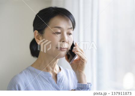 スマートフォンで通話する50代後半の女性 137911873