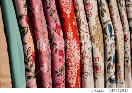 Close-up of colorful hand-woven fabrics with floral and pomegranate patterns, soft lighting Close-up of colorful hand-woven fabrics with floral and pomegranate patterns, soft lighting 137912913