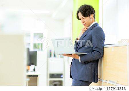 オフィスでノートパソコンで仕事をする男性 オフィスでノートパソコンで仕事をする男性 137913218