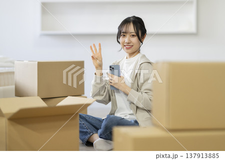 段ボール箱に囲まれて座る笑顔の若い女性　カメラ目線　引っ越し　イメージ 137913885