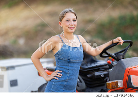 Young woman posing near tractor in countryside Young woman posing near tractor in countryside 137914566