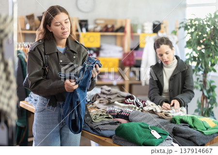 Attentive young girl choosing jean pantaloons in clothing store 137914667
