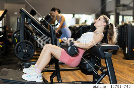 Sportive young girl training on hip thrust machine in gym Sportive young girl training on hip thrust machine in gym 137914740
