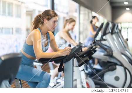 Woman exercising on an exercise bike in the gym Woman exercising on an exercise bike in the gym 137914753