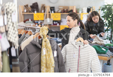 Adult woman choosing down jacket in clothing store Adult woman choosing down jacket in clothing store 137914764