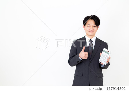電卓を持ってガッツポーズするスーツを着たミドル男性ビジネスマン 137914802