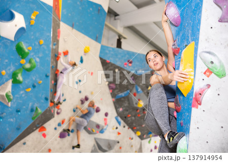 Focused sporty young girl climbing on bouldering wall 137914954