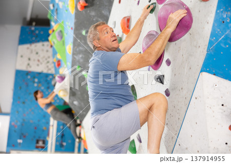 Adult man practicing rock climbing on climbing wall Adult man practicing rock climbing on climbing wall 137914955
