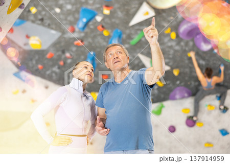 Adult woman and adult man posing on climbing wall 137914959