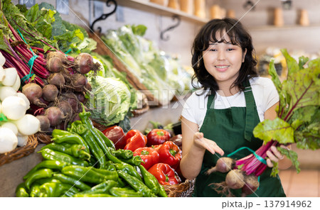 Smiling young saleswoman holding beetroots in grocery store Smiling young saleswoman holding beetroots in grocery store 137914962