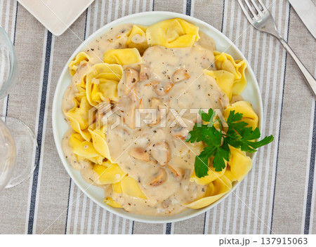 Portion of fresh ravioli is served on plate, drizzled with mushroom sauce. Decorated by parsley Portion of fresh ravioli is served on plate, drizzled with mushroom sauce. Decorated by parsley 137915063