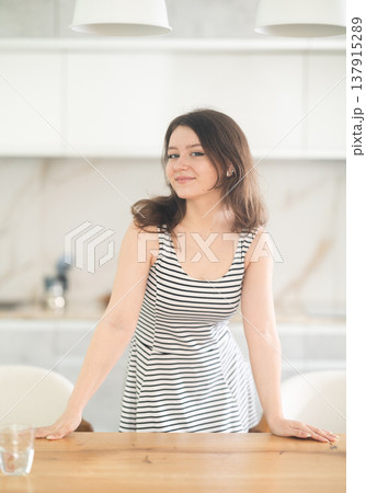 Smiling young woman standing at table 137915289