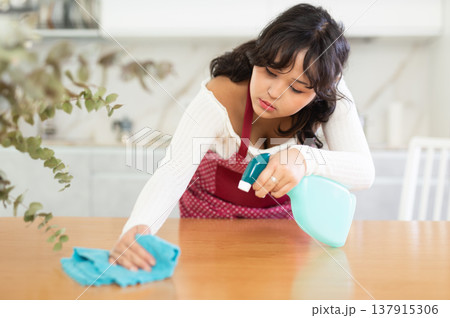 Housewife cleaning table surface with rag in modern kitchen Housewife cleaning table surface with rag in modern kitchen 137915306