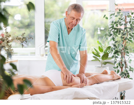 Skilled old masseur conducting hip massage for woman client Skilled old masseur conducting hip massage for woman client 137915322