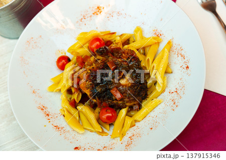 Boiled pasta with piece of fried chicken is served on large white platter. 137915346
