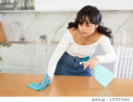 Girl washing of kitchen table during cleanup in apartment Girl washing of kitchen table during cleanup in apartment 137915362