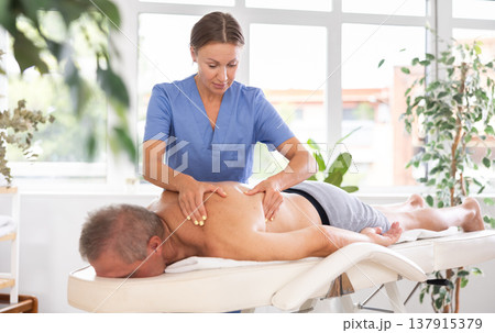 masseuse giving massage to male patient masseuse giving massage to male patient 137915379