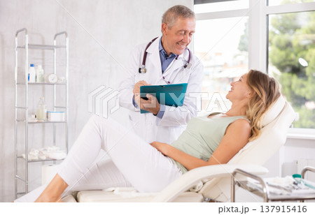 Male doctor carries out questionnaire survey of woman after procedure Male doctor carries out questionnaire survey of woman after procedure 137915416