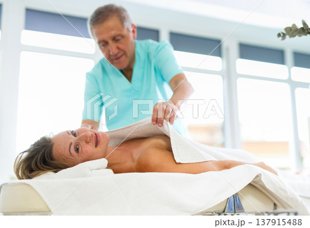 female patient under towel on massage table 137915488