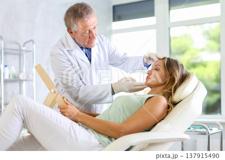 Elderly man doctor examining adult woman patient 137915490