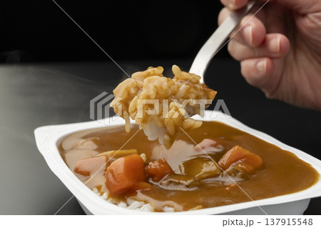 レトルトカレーをかけたパックご飯をスプーンで持ち上げる　 137915548