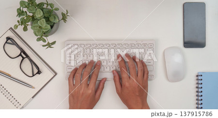 Typing on keyboard in organized workspace Typing on keyboard in organized workspace 137915786