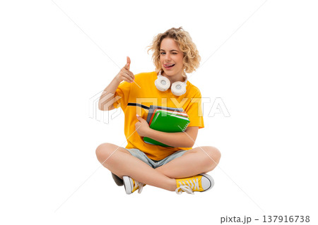 A student sits smiling with books in hand, isolated, PNG A student sits smiling with books in hand, isolated, PNG 137916738