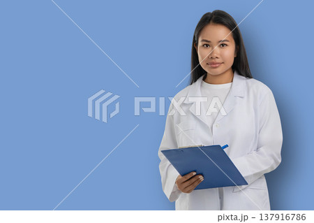 Medical worker in white coat stands holding clipboard 137916786